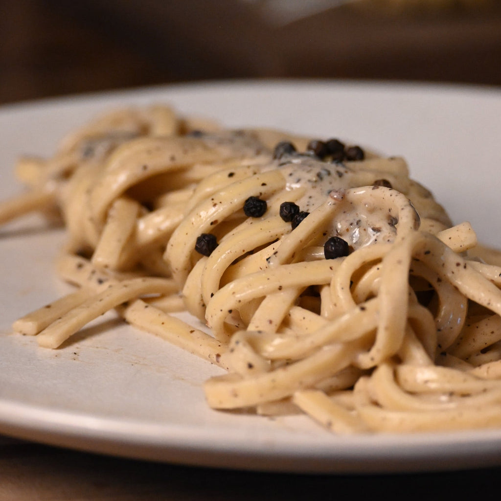 Plate of fettuccine cacio e pepe with a creamy sauce and black pepper on a wooden table