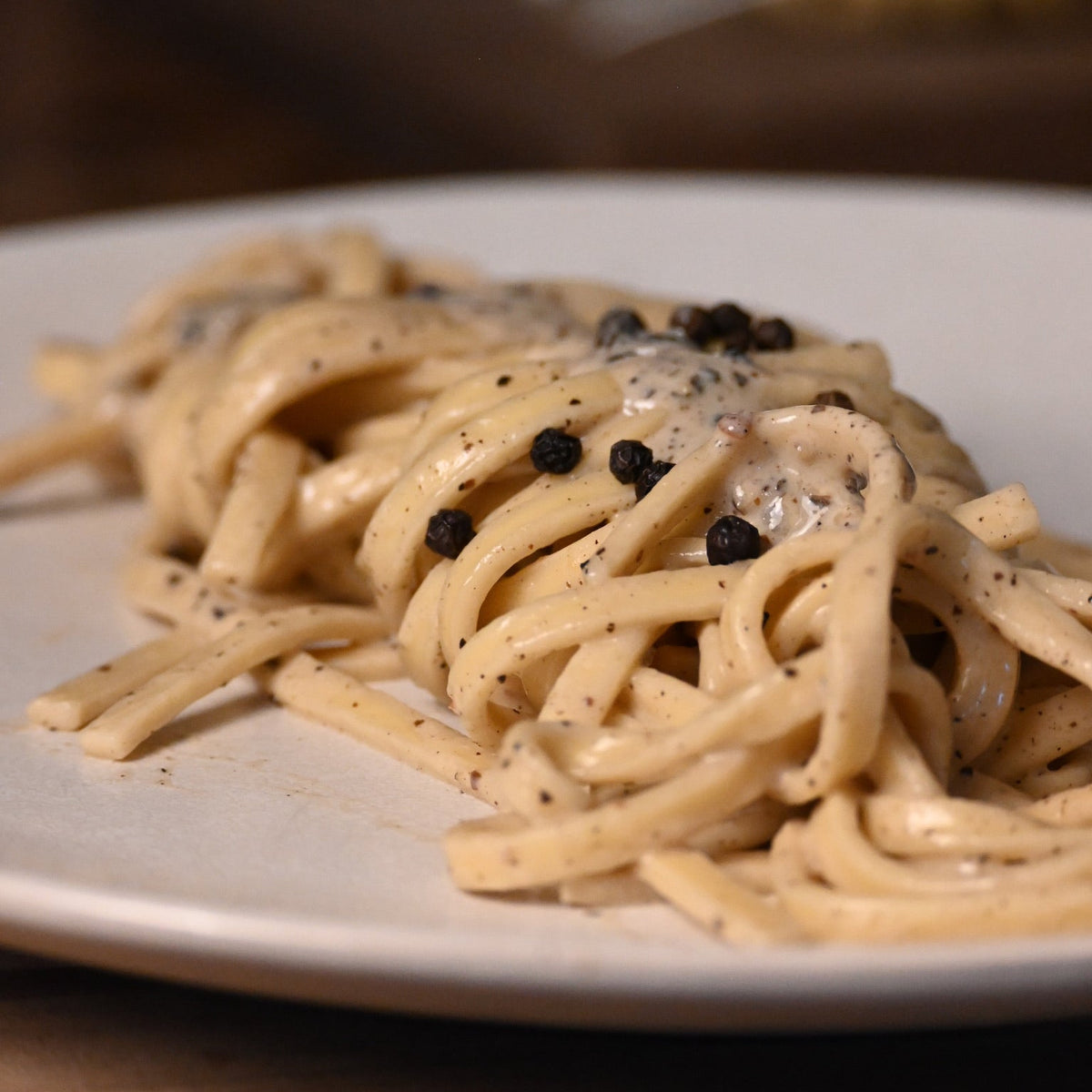 Plate of fettuccine cacio e pepe with a creamy sauce and black pepper on a wooden table