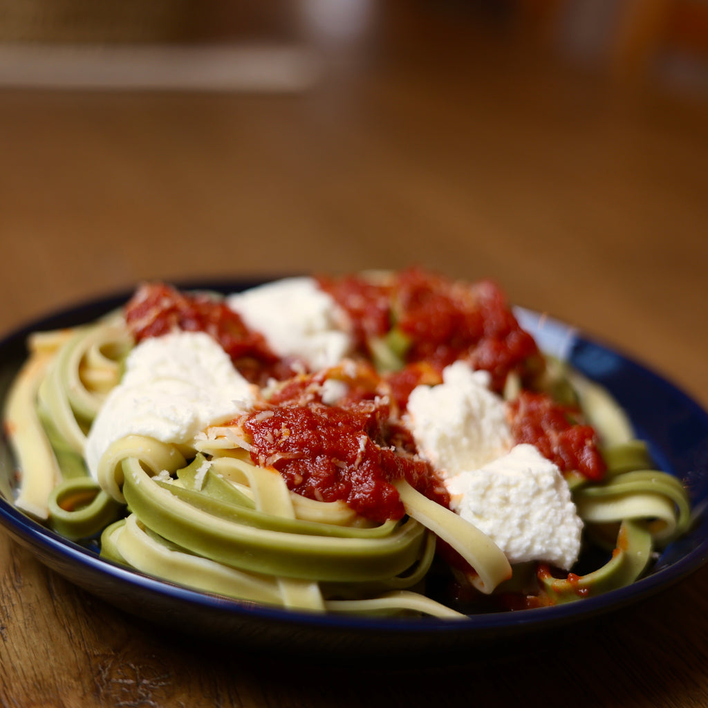 Plate of pasta with tomato sauce and cheese on a wooden table