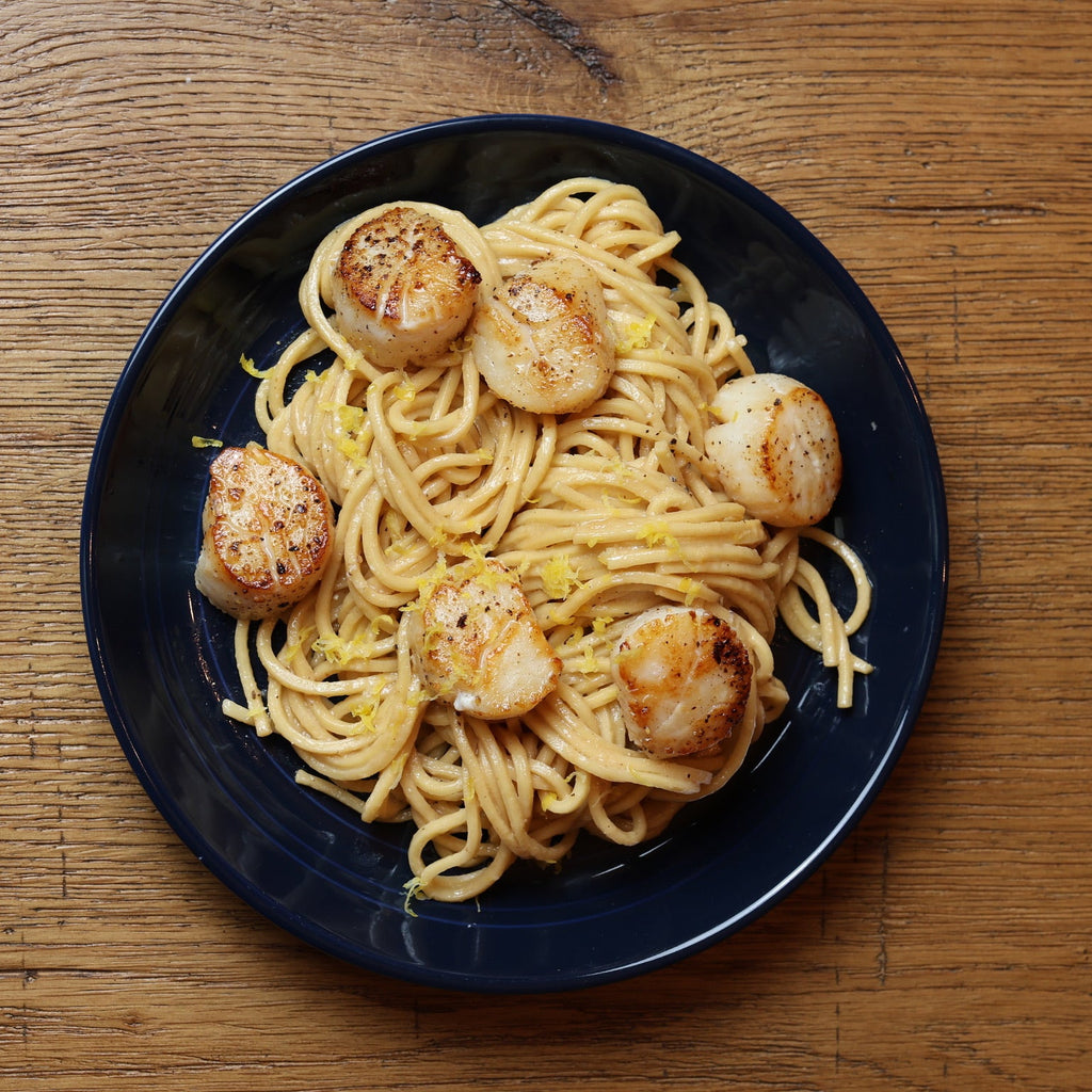 Plate of Linguine with scallops on a wooden table
