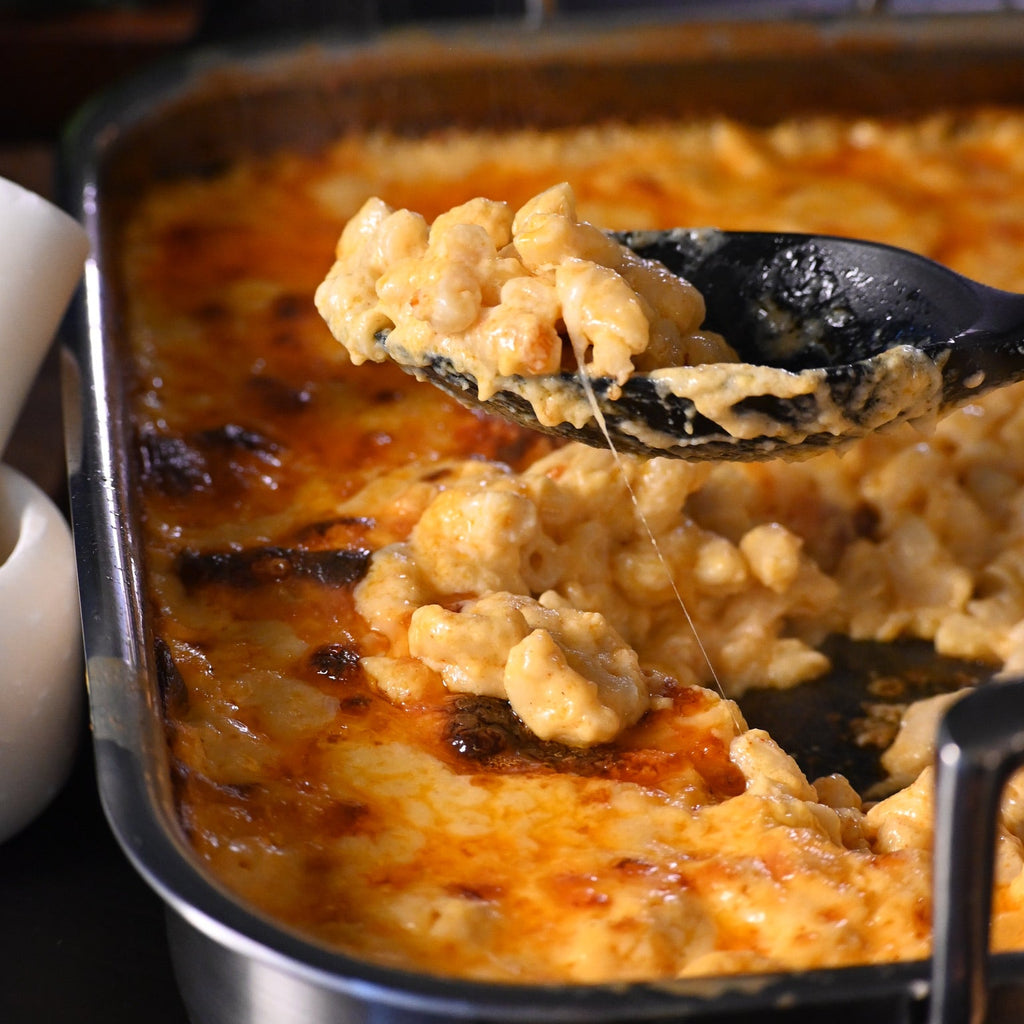 Macaroni and cheese being scooped out of a baking dish with a black spoon.