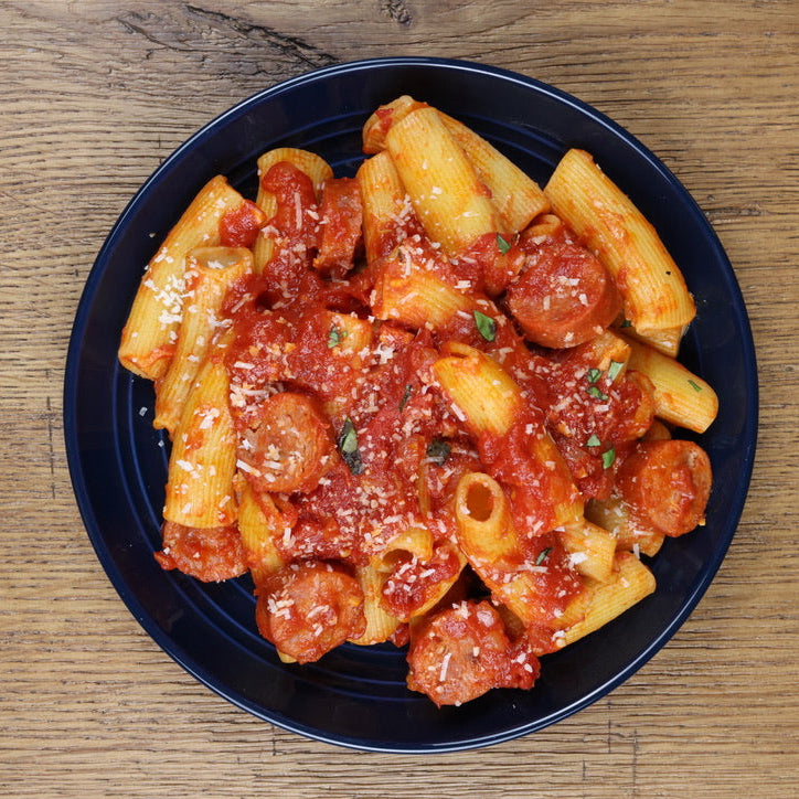 Rigatoni dish with tomato sauce on a blue plate on a wooden table