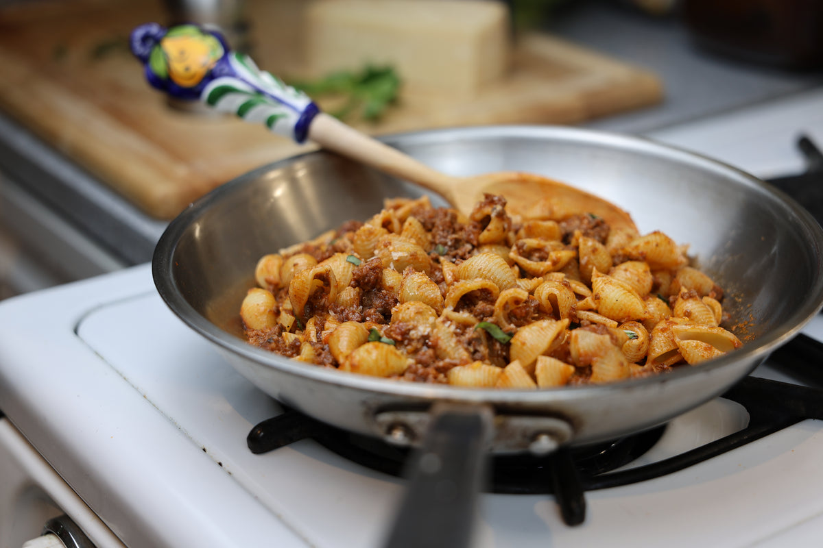 Shell dish in a pan on a stove with a wooden spoon